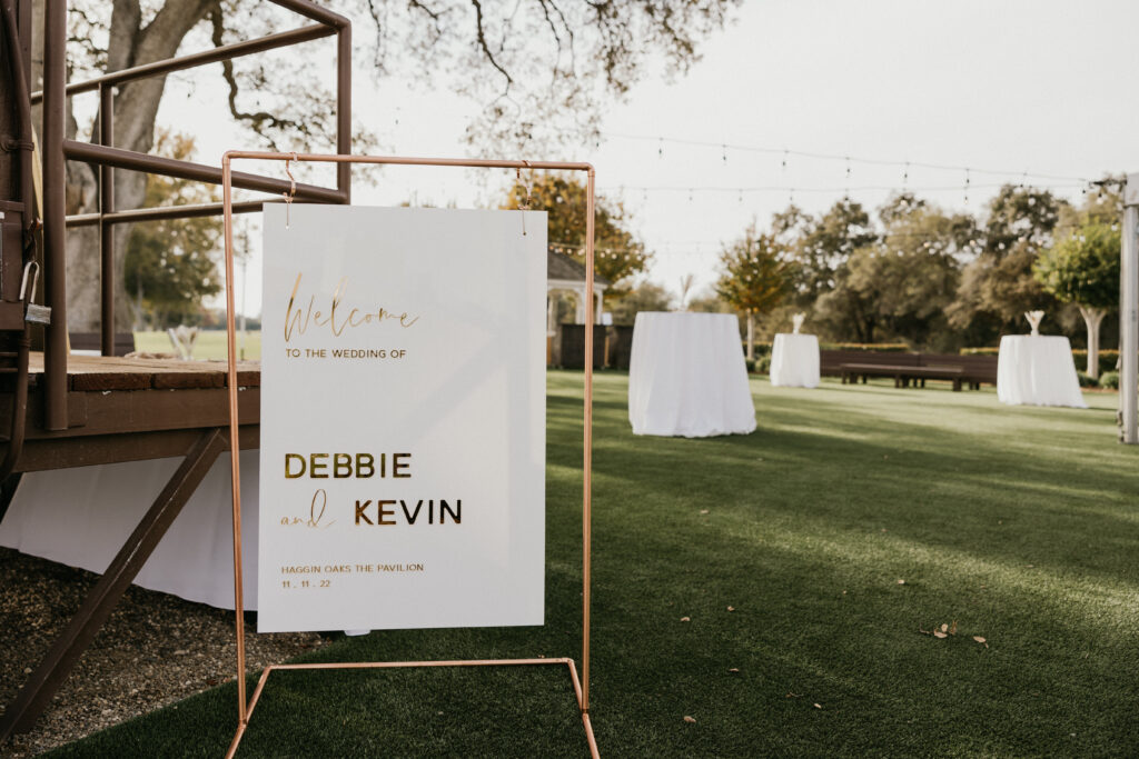 Wedding welcome sign displayed on the event lawn at The Pavilion at Haggin Oaks, greeting guests before an outdoor wedding reception in Sacramento.