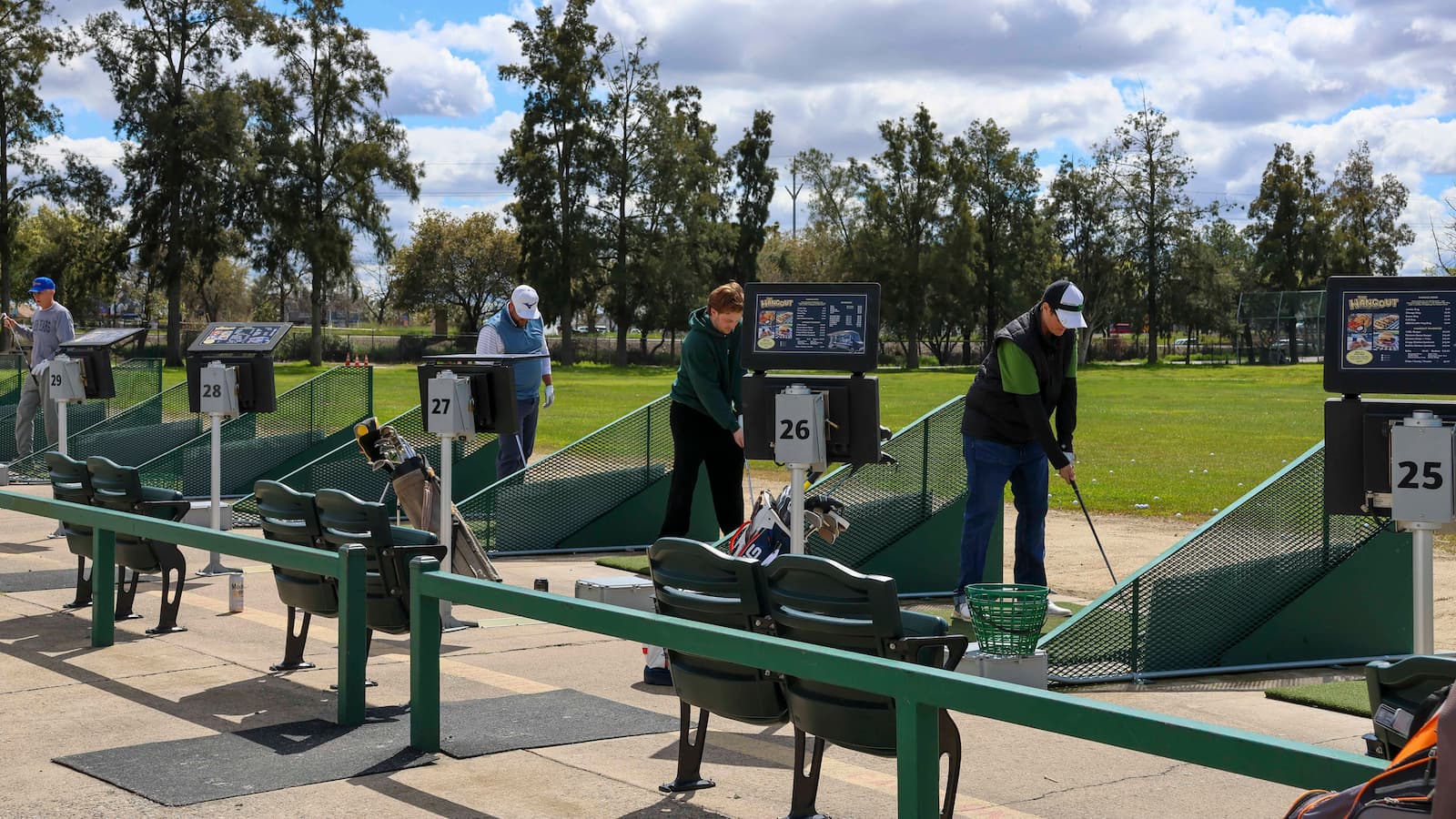 Golfers practicing from individual hitting bays at The Hangout driving range at Haggin Oaks Golf Complex in Sacramento.