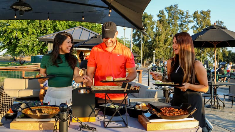Friends enjoying pizza and food at The Hangout outdoor patio and driving range at Haggin Oaks Golf Complex in Sacramento.