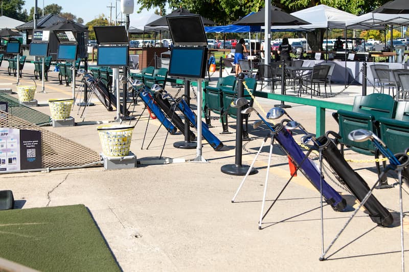 Golf practice bays with golf clubs and ball baskets at The Hangout driving range at Haggin Oaks Golf Complex in Sacramento.